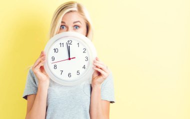  Saati yaklaşık 12 gösteren tutan kadın
