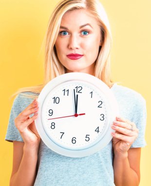  Saati yaklaşık 12 gösteren tutan kadın