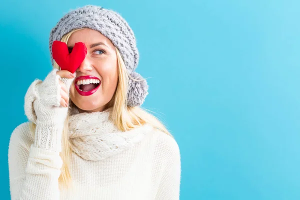 Happy young woman holding a heart cushion — Stock Photo, Image