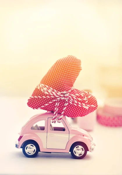 Miniature pink car carrying heart cushion — Stock Photo, Image