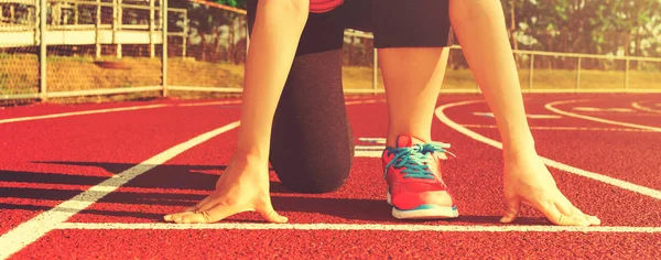 Vrouwelijke atleet op de startlijn van een stadion-track — Stockfoto