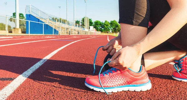 Θηλυκό jogger δένοντας τα παπούτσια σε ένα κομμάτι στάδιο — Φωτογραφία Αρχείου