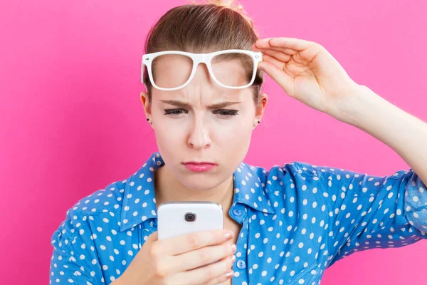Ung kvinna stirrar på hennes mobiltelefon — Stockfoto