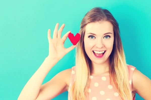 Happy young woman holding a heart cushion — Stock Photo, Image