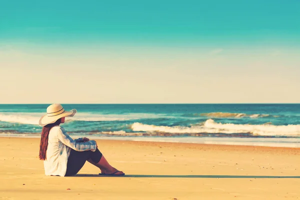 Mujer con sombrero sentada en la playa —  Fotos de Stock