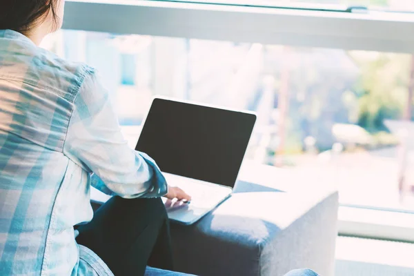 Женщина на ноутбуке в светлой комнате с окном — стоковое фото