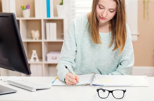 Jonge vrouw die werkt aan een bureau in haar kantoor aan huis — Stockfoto