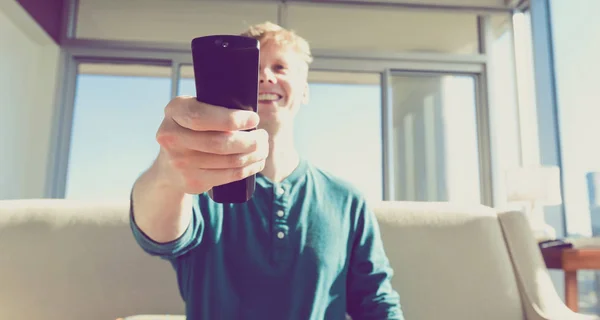 Joven hombre usando tv control remoto — Foto de Stock