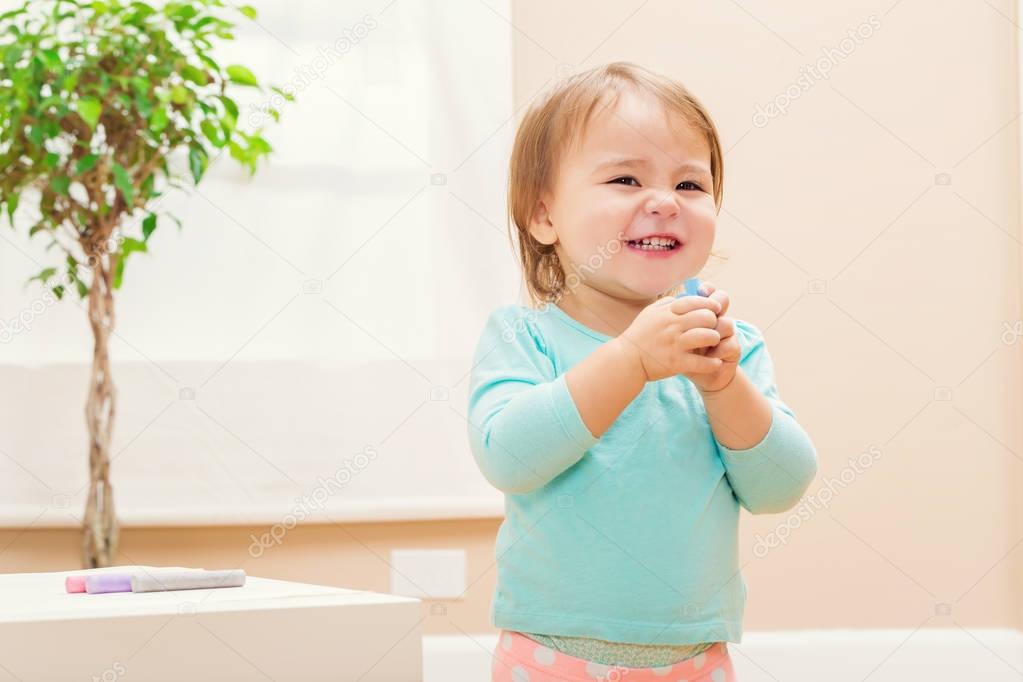 Happy toddler girl playing with chalk 