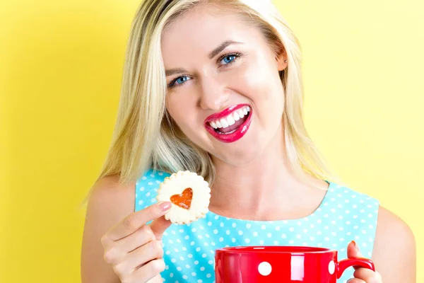 Счастливая молодая женщина с печеньем и кофе — стоковое фото