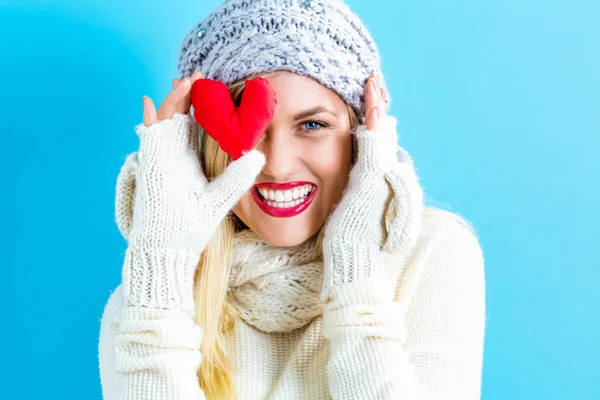 Happy young woman holding a heart cushion — Stock Photo, Image