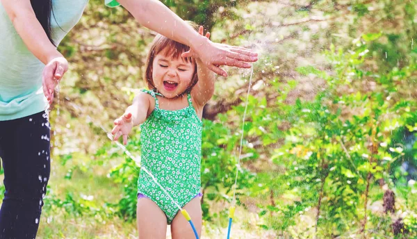 Menina da criança brincando em um aspersor — Fotografia de Stock