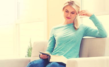 Kadın evde kitap okuyor.