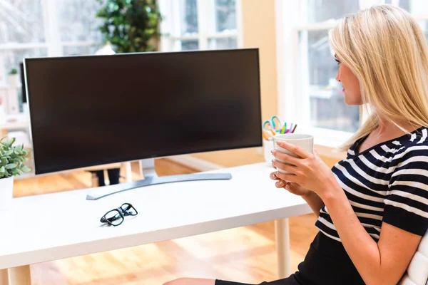 Frau sitzt vor großem Bildschirm — Stockfoto