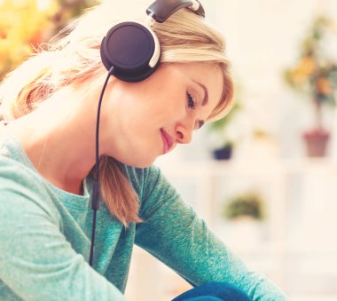 Kadın kulaklıkla müzik dinliyor.