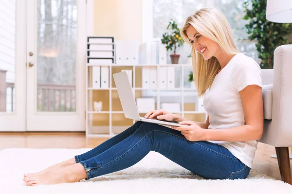 Ung kvinna som använder laptop hemma — Stockfoto