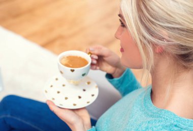 Genç bayan bir fincan kahve içiyor.