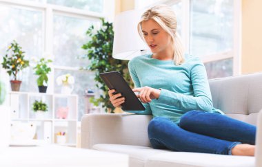 Mutlu genç kadın tabletini kullanıyor.