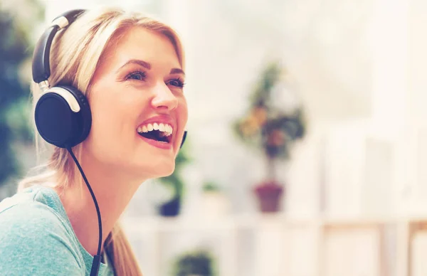 Mladá žena poslouchající hudbu na sluchátkách — Stock fotografie