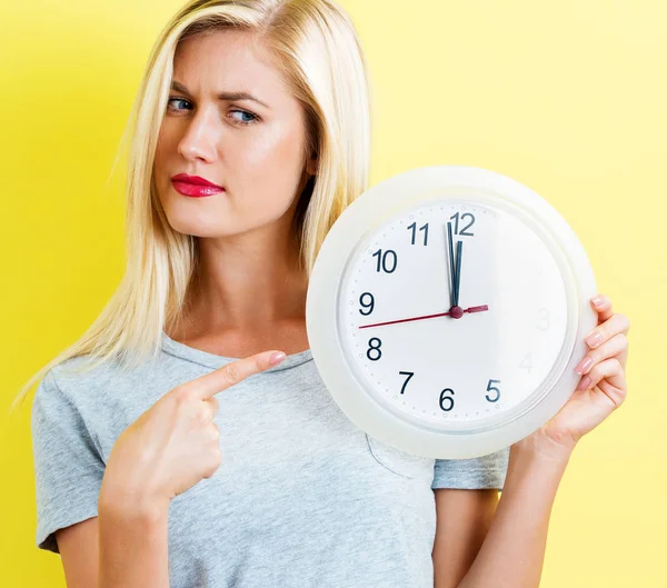 महिला घड़ी पकड़ रही है लगभग 12 दिखा रही है — स्टॉक फ़ोटो, इमेज