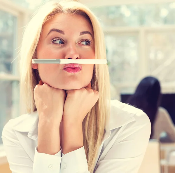 Jonge vrouw die een pen boven de lippen houdt — Stockfoto