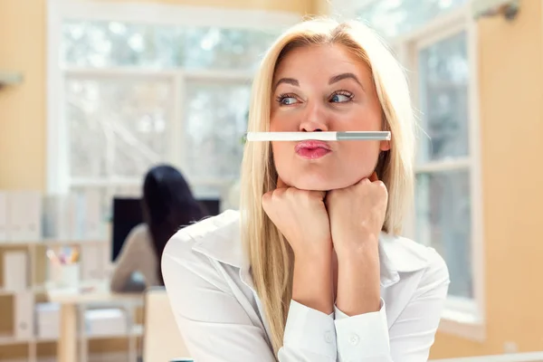 Young woman holding a pen above lips — Stock Photo, Image