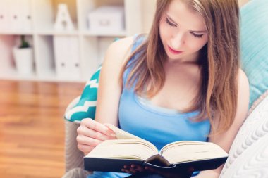 Genç kadın onun kanepenin üzerine bir kitap okuma 