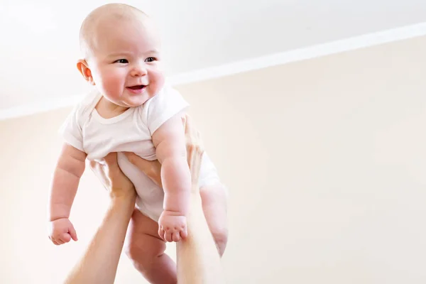Happy infant baby girl being held up in the air — Stock Photo, Image