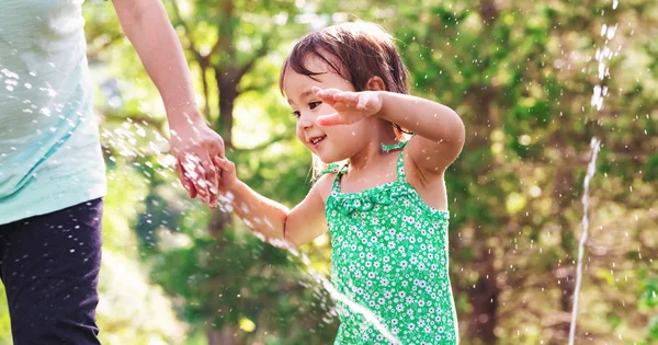 Kisgyermek lány játszik egy sprinkler — Stock Fotó