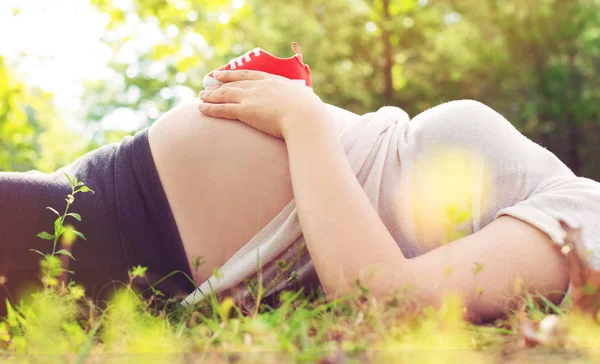 Femme enceinte tenant des chaussures de bébé — Photo