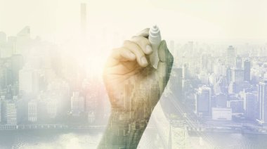 bir kalem ve şehir arka plan tutan el