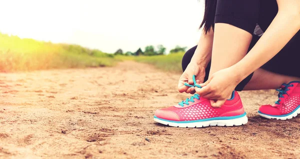 Runner tying her running shoes — Stock Photo, Image