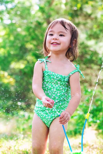 Happy toddler girl playing with sprinkler — Stock Photo, Image