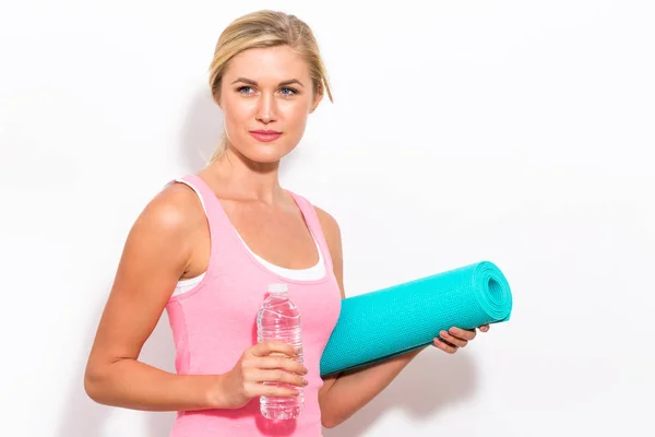 Kvinde holder yogamåtte og vandflaske - Stock-foto