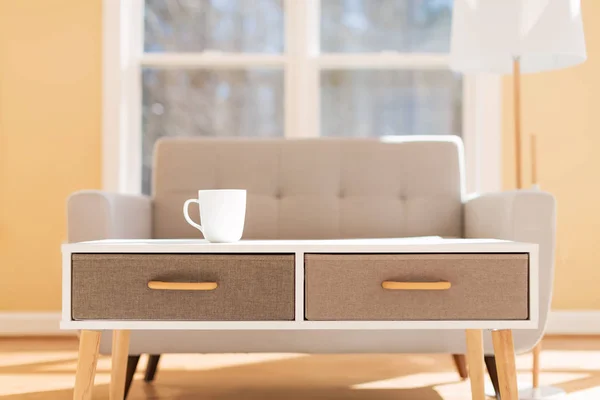 Coffee cup and gray midcentury loveseat — Stock Photo, Image