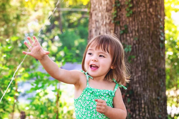 スプリンクラーで遊ぶ幼児の女の子 — ストック写真