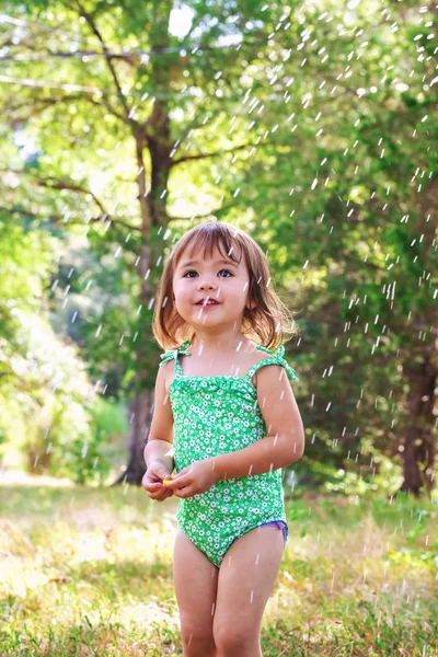 Toddler girl playing with sprinkler — Stock Photo, Image