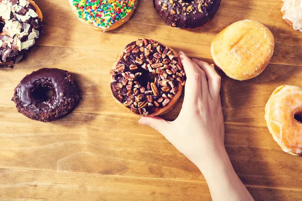 Person placing assorted donuts — Stock Photo, Image