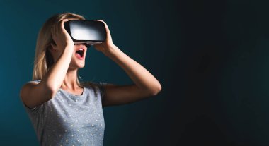 Sanal gerçeklik kulaklığı kullanan genç bir kadın.