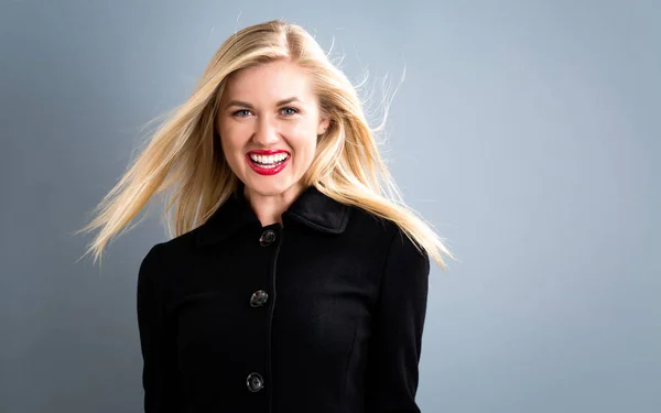 Mooie blonde vrouw in een zwarte jas — Stockfoto