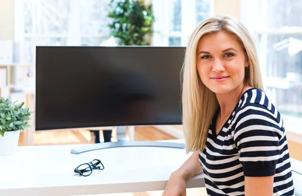 Jovem sentada na frente do grande monitor — Fotografia de Stock