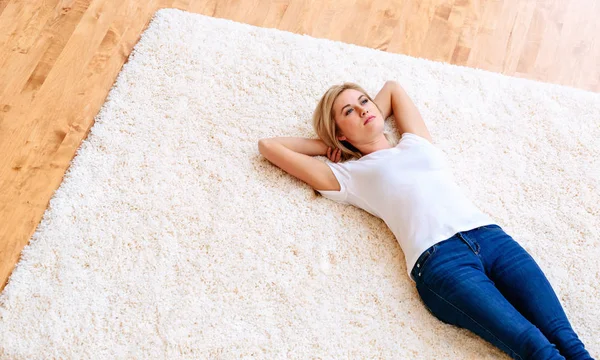 Молода жінка лежить на килимі — стокове фото