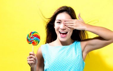 Genç bir kadın lolipop tutuyor.