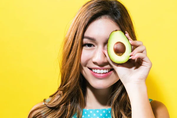 O femeie tânără fericită care ține avocado jumătate — Fotografie, imagine de stoc