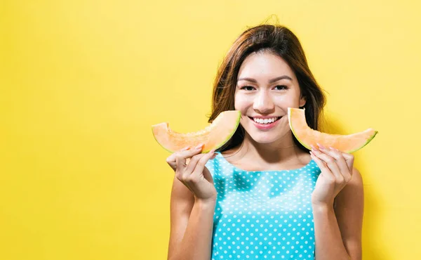 Happy young woman holding slices of cantaloupe — Stock Photo, Image