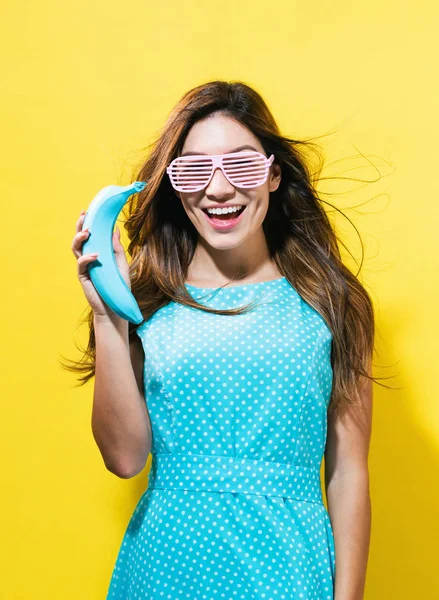 Happy young woman holding a colored banana — Stock Photo, Image