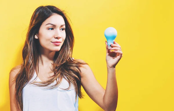 Mujer joven sosteniendo una bombilla — Foto de Stock