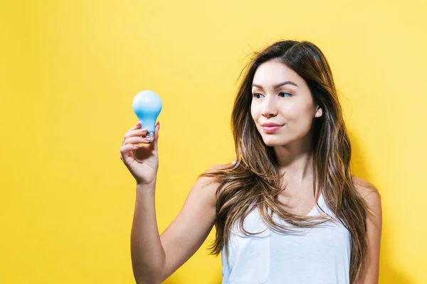 Giovane donna che tiene una lampadina — Foto Stock