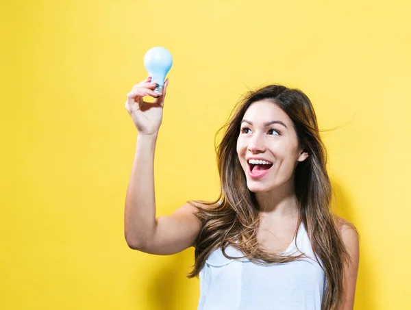 Mujer joven sosteniendo una bombilla —  Fotos de Stock