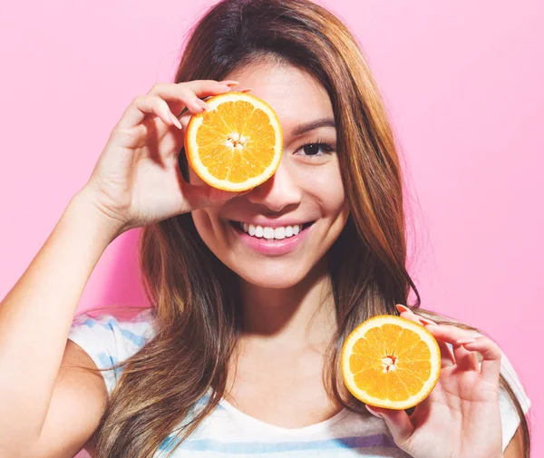 Jovem feliz segurando laranjas metades — Fotografia de Stock